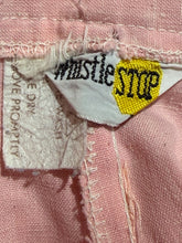 Load image into Gallery viewer, Close-up of a pink garment's inner label area, showing a white woven brand tag that reads 'whistle STOP' with a yellow STOP shape 
