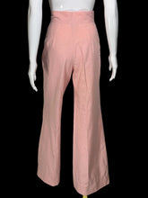 Load image into Gallery viewer, A pair of high-waisted, wide-leg pink pants displayed on a white mannequin. The pants feature a buttoned waistband with gold-tone buttons.
