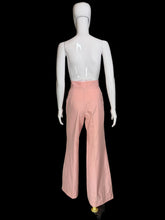 Load image into Gallery viewer, A pair of high-waisted, wide-leg pink pants displayed on a white mannequin. The pants feature a buttoned waistband with gold-tone buttons.
