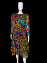 Load image into Gallery viewer, A long-sleeve tiered dress displayed on a white mannequin, featuring a highly vibrant, multicolored psychedelic abstract pattern with swirls, paisley, and checkerboard motifs.
