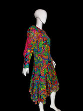 Load image into Gallery viewer, A long-sleeve tiered dress displayed on a white mannequin, featuring a highly vibrant, multicolored psychedelic abstract pattern with swirls, paisley, and checkerboard motifs.
