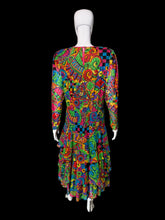 Load image into Gallery viewer, A back view of a long-sleeve tiered dress displayed on a white mannequin, featuring a highly vibrant, multicolored psychedelic abstract pattern with swirls, paisley, and checkerboard motifs.
