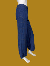 Load image into Gallery viewer, A pair of wide-leg blue denim jeans with checkered stitching displayed on a white mannequin.
