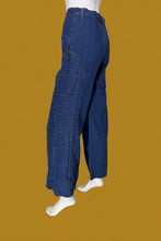 Load image into Gallery viewer, A pair of wide-leg blue denim jeans with checkered stitching displayed on a white mannequin.
