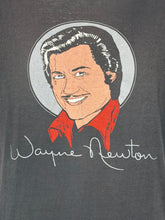 Load image into Gallery viewer, A close-up of a dark gray graphic t-shirt featuring a stylized portrait of Wayne Newton inside a circular frame, with his name written in white script below.
