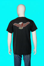 Load image into Gallery viewer, A black short-sleeve t-shirt displayed on a white mannequin torso, showing a large graphic of an eagle with spread wings on the back. The graphic features red and white patterned wings, a white head, and a small yellow accent.
