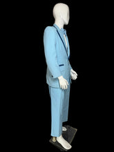 Load image into Gallery viewer, A light blue suit displayed on a white mannequin. The suit features dark blue contrast piping along the lapels and pocket edges, and is styled with a matching light blue bow tie and white dress shirt.
