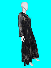 Load image into Gallery viewer, A black long-sleeve maxi dress with metallic gold abstract patterns, displayed on a white mannequin.

