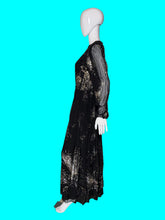 Load image into Gallery viewer, A long black dress with sheer sleeves and a metallic gold abstract floral pattern, displayed on a white mannequin.
