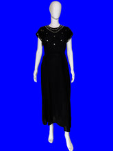 Load image into Gallery viewer, A black midi-length dress with cap sleeves and silver embellishments around the neckline, displayed on a white mannequin.
