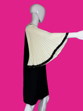 Load image into Gallery viewer, A mannequin wearing a black dress with its arm up to display the dramatic accordion bell sleeve.
