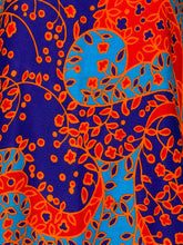 Load image into Gallery viewer, A close-up of a vibrant fabric pattern featuring bright orange floral and vine motifs over a blue background.
