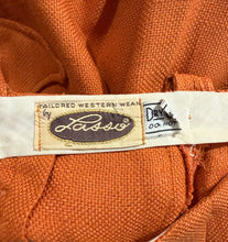 Load image into Gallery viewer, Close-up of an orange woven textile garment with a cream fabric brand label reading 'Tailored Western Wear by Lasso'
