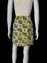 Load image into Gallery viewer, A high-waisted, pleated mini skirt featuring a colorful patchwork print of vintage comic book panels with text like 'PLEASE BE SEATED' and 'THAT'S ALL FOLKS!'.
