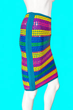 Load image into Gallery viewer, A colorful striped skirt displayed on a white mannequin from the side, featuring horizontal bands of yellow, blue, green, and magenta sequins with a teal border.
