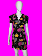 Load image into Gallery viewer, A short-sleeve black dress with a colorful floral print, displayed on a white mannequin.
