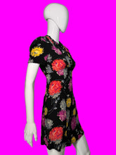Load image into Gallery viewer, A short-sleeve black dress with a colorful floral print, displayed on a white mannequin from the side.
