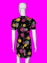 Load image into Gallery viewer, A short-sleeve black dress with a colorful floral print, displayed on a white mannequin from the back.
