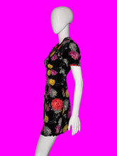 Load image into Gallery viewer, A short-sleeve black dress with a colorful floral print, displayed on a white mannequin from the side.
