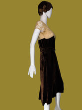 Load image into Gallery viewer, A dark brown velvet 1920s midi length dress displayed on a white mannequin. The set includes a matching brown head covering. 
