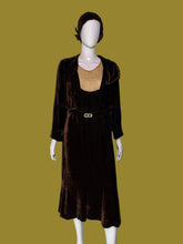 Load image into Gallery viewer, A dark brown velvet 1920s midi length dress with a matching long sleeve cropped brown velvet jacket displayed on a white mannequin. The set includes a matching brown head covering. 
