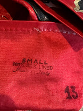 Load image into Gallery viewer, Close-up of a red fabric showing printed size information that reads 'SMALL 100% SILK LINED Made in Italy' and the number '13'.

