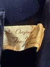 Load image into Gallery viewer, Close-up of a fabric label sewn onto dark navy blue lining, with cursive text partially visible reading 'An Original Free-Mor Creation'
