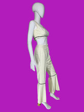 Load image into Gallery viewer, A cream-colored two-piece outfit displayed on a white mannequin. The set includes a sleeveless crop top with black dashed trim and matching high-waisted flared pants with black dashed trim and decorative buttons on the back.
