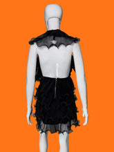 Load image into Gallery viewer, Black ruffled tulle dress shown on a white mannequin featuring a tiered ruffle skirt and a sheer ruffled dramatic collar shown from the back highlight the low back.
