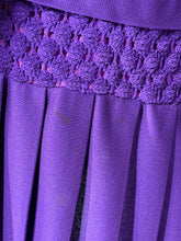 Load image into Gallery viewer, Close-up of a purple pleated skirt with a textured lace or crochet waistband displayiing a small stain on one of the pleats. 
