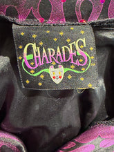 Load image into Gallery viewer, Black fabric tag reading 'CHARADES' with a theatrical mask logo sewn into a black and purple metallic garment. 
