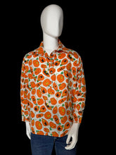 Load image into Gallery viewer, A long-sleeve button-up shirt with an all-over orange jack-o'-lantern pattern on a white background, displayed on a white mannequin torso.
