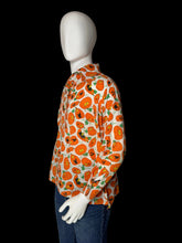 Load image into Gallery viewer, A long-sleeve button-up shirt with an all-over orange jack-o'-lantern pattern on a white background, displayed on a white mannequin torso.
