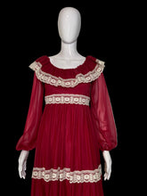 Load image into Gallery viewer, A long maroon chiffon and lace prairie dress displayed on a white mannequin from the front and back, featuring sheer long sleeves, a square neckline with cream lace trim, and matching lace bands at the waist and hem.
