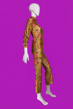 Load image into Gallery viewer, A two-piece matching long-sleeve top and cropped pants set displayed on a white mannequin. The set features a vibrant, dense retro pattern in orange, yellow, red, and black, with a high mock neck and cropped ankle-length legs.
