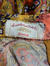 Load image into Gallery viewer, Close-up of a colorful patterned textile with a sewn-on fabric label reading 'Specially Hand Made By Elizabeth'.
