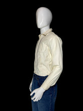 Load image into Gallery viewer, A cream-colored long-sleeve jacket displayed on a white mannequin torso, shown from a side profile.
