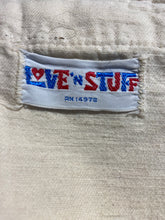 Load image into Gallery viewer, Close-up of a fabric garment with a sewn-on label reading "LOVE 'N STUFF"
