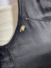 Load image into Gallery viewer, A small tear shown at the armpit of a black satin garment. 
