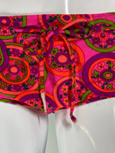 Load image into Gallery viewer, A close-up of a colorful fabric item, likely a bikini bottom or dress panel, featuring a retro circular pattern in pink, purple, orange, and green. The fabric is gathered and tied at the waist.

