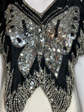 Load image into Gallery viewer, A close-up of a black embellished garment featuring large silver sequined butterfly wings and metallic silver beadwork on a white mannequin torso.
