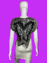Load image into Gallery viewer, A black and silver sequined embellished top displayed on a white mannequin torso, paired with a cream-colored skirt.
