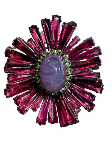 Decorative brooch with pink and green gemstones on a light gray background