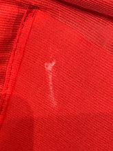Load image into Gallery viewer, Close-up of red fabric  lining  with a visible white mark.
